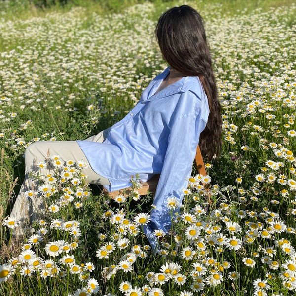 Person stretching gently outdoors with a green natural background.